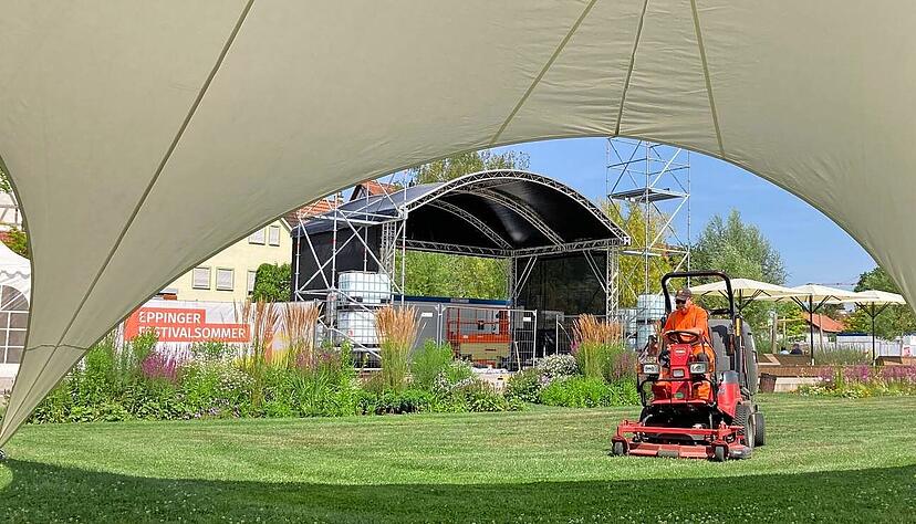 Letzte Vorbereitungen: Ein Mitarbeiter des Bauhofs mäht den Rasen vor der Bühne im Weiherpark. Pavillons für Gastronomie und zum Entspannen im Schatten stehen bereits.
Foto: Jörg Kühl