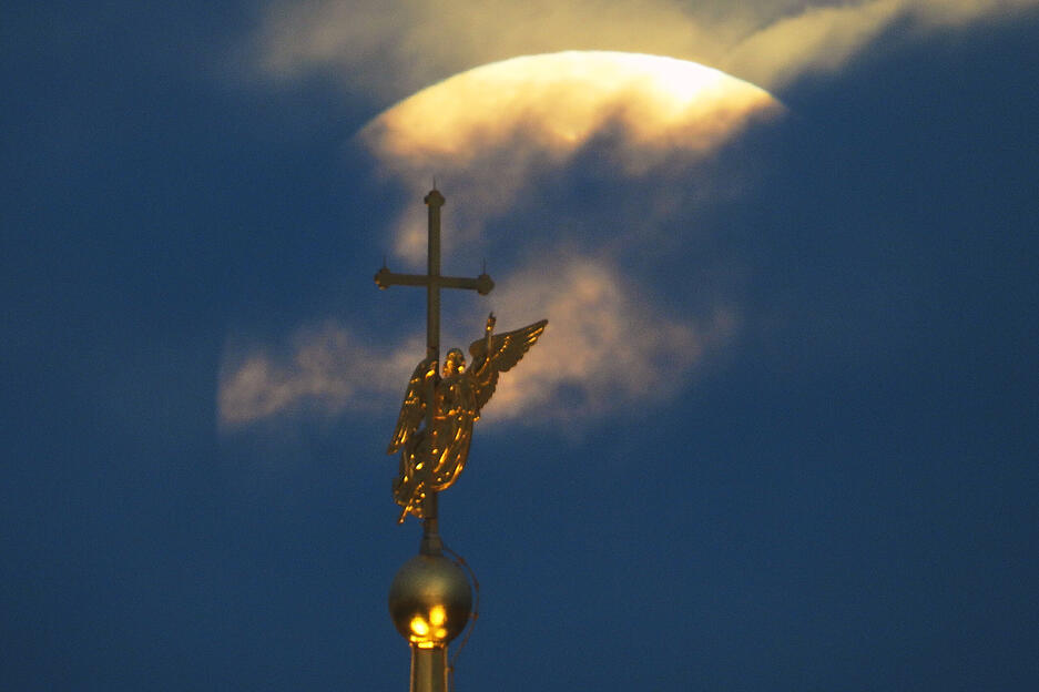 Hinter den Wolken versteckt sich der Supermond in Russland. Im Vordergrund ist die Wetterfahne der Peter-und-Paul-Kathedrale in St. Petersburg zu sehen.