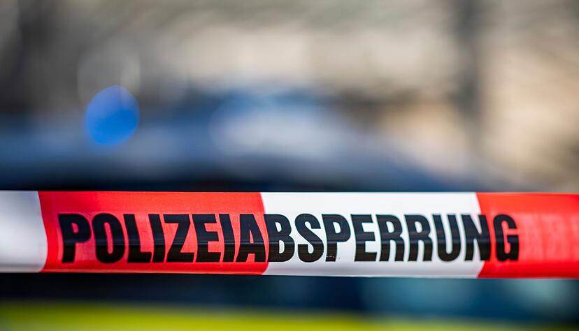 Ein Absperrband mit der Aufschrift «Polizeiabsperrung» ist vor einem Polizeiwagen aufgespannt.