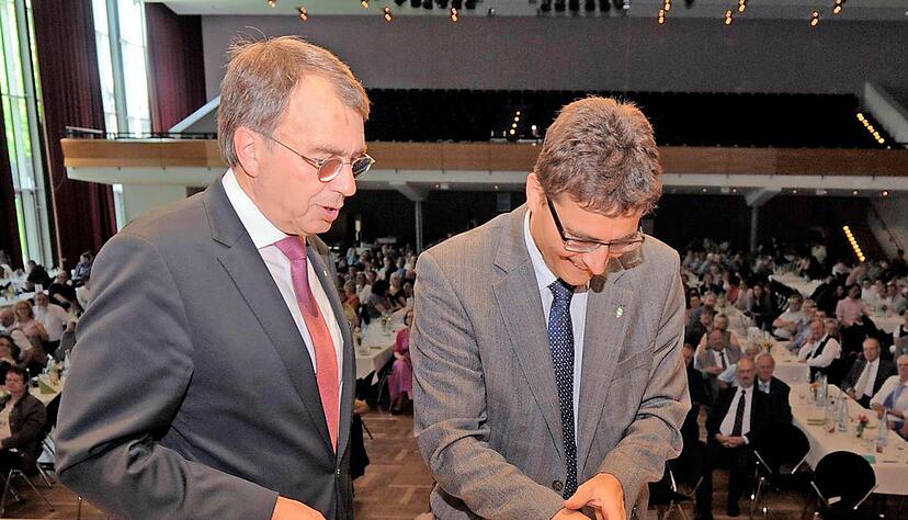 Die Geburtstagstorte mit einer 50 im Lorbeerkranz und der grünen schützenden Hand, dem bleibenden Emblem des Sozialwerks. Hans-Christoph Ketelhut (r.) schreitet zur Tat. Ihm steht Oberkirchenrat Dieter Kaufmann zur Seite.Foto: Dennis Mugler