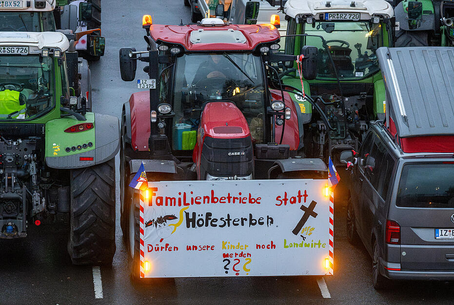 Ein Schild mit der Aufschrift „Familienhöfe statt Höfesterben“ ist auf einem Traktor auf der Straße des 17. Juni angebracht.