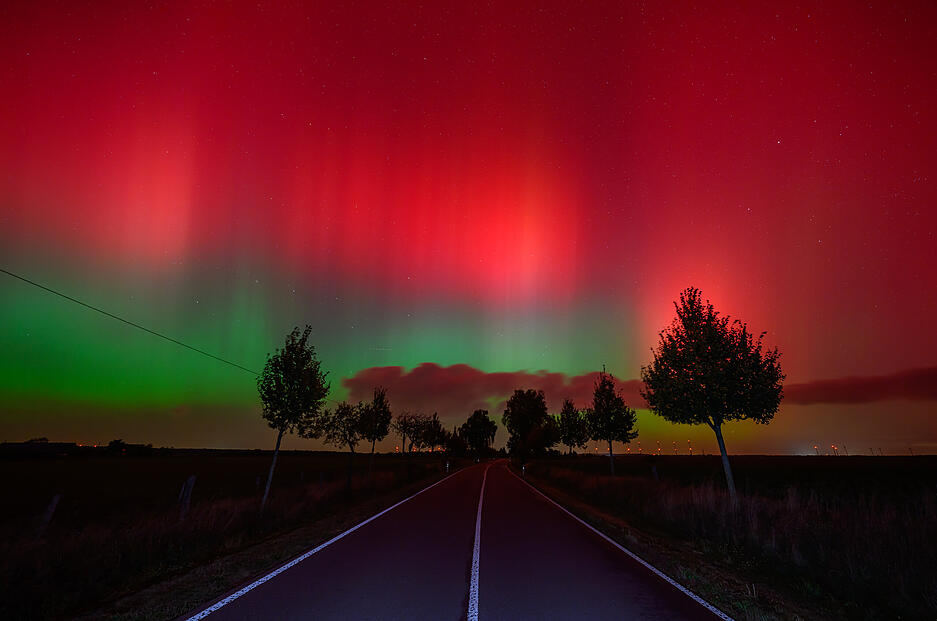 Polarlichter leuchten am Nachthimmel über einer Straße im östlichen Brandenburg.