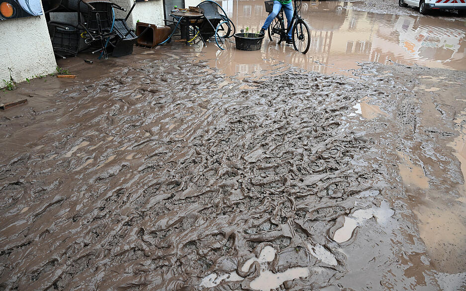 Auf einer nach einem Unwetter verschlammten Straße sind Spuren von Fußgängern. Auf einer nach einem Unwetter verschlammten Straße sind Spuren von Fußgängern.