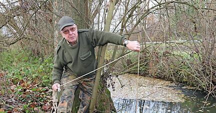 Rolf Reichert zieht eine dunkelbraune Reuse aus der Brettach. Drei Krebse haben sich in dem Plastikk&auml;fig verfangen.