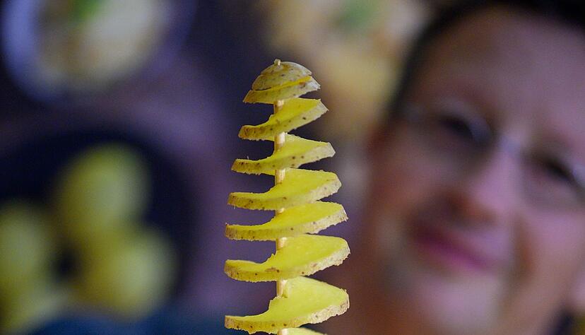 Kartoffelexperte Steffen Lange zeigt, wie die Kartoffelspirale aussehen muss, wenn sie auf den Spie&szlig; aufgezogen wurde.
