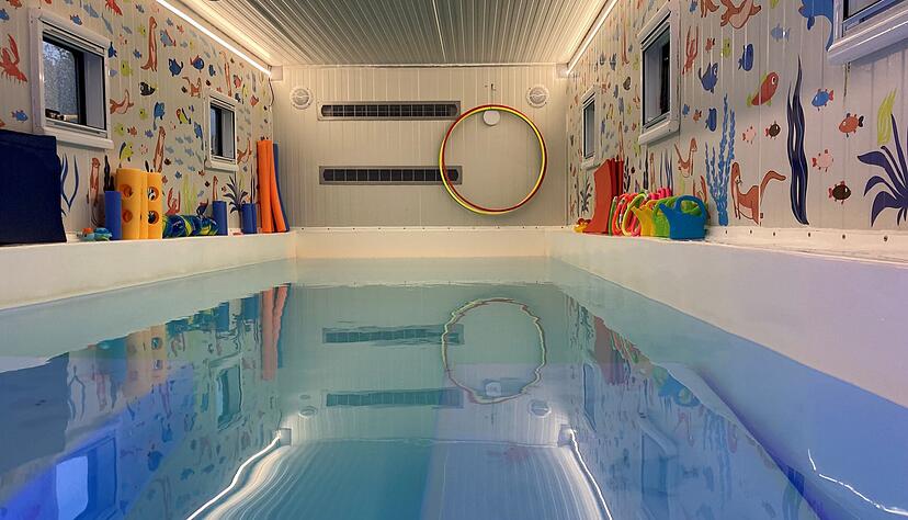 Am Beckenrand sind Gießkännchen, Quietscheenten und Poolnudeln aufgereiht. Der Einstieg ins Schwimmen geht im 31 Grad warmen Wasser der „Wundine on wheels“ spielerisch vonstatten.