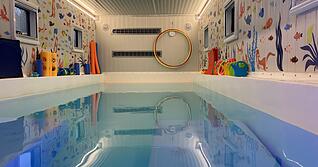 Am Beckenrand sind Gießkännchen, Quietscheenten und Poolnudeln aufgereiht. Der Einstieg ins Schwimmen geht im 31 Grad warmen Wasser der „Wundine on wheels“ spielerisch vonstatten.