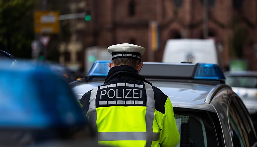 Ein Polizeibeamter steht zwischen zwei Einsatzfahrzeugen der Polizei. Ein Polizeibeamter steht zwischen zwei Einsatzfahrzeugen der Polizei.