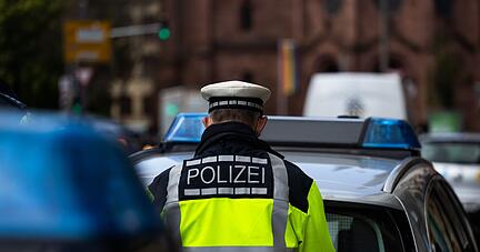 Ein Polizeibeamter steht zwischen zwei Einsatzfahrzeugen der Polizei. Ein Polizeibeamter steht zwischen zwei Einsatzfahrzeugen der Polizei.
