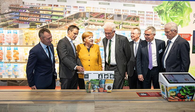 Angela Merkel und Winfried Kretschmann lassen sich von dem zuk&uuml;nftigen Vorstand der Klimastiftung f&uuml;r B&uuml;rger, Bernd Welz (2. von links), den Klimasupermarkt erkl&auml;ren.
Fotos: Veigel, Andreas