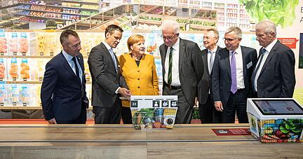 Angela Merkel und Winfried Kretschmann lassen sich von dem zuk&uuml;nftigen Vorstand der Klimastiftung f&uuml;r B&uuml;rger, Bernd Welz (2. von links), den Klimasupermarkt erkl&auml;ren.
Fotos: Veigel, Andreas