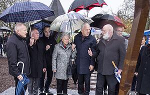 Die Linie aus massivem Stahl setzt sich als Spiegelbild fort. K&uuml;nstler Robert Schad (mit wei&szlig;em Bart) erkl&auml;rt OB Harry Mergel sowie Angeh&ouml;rigen und Freunden der Familie Fuchs sein Werk. 
Fotos: Mario Berger