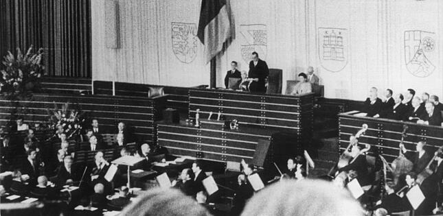 Alterspr&auml;sident Paul L&ouml;be (M), spricht w&auml;hrend der konstituierenden Sitzung des Deutschen Bundestages in der einstigen Turnhalle der P&auml;dagogischen Akademie, die zuvor zum Plenarsaal umgebaut worden war. Eingeleitet wurde die Sitzung mit Beethovens festlicher Ouvert&uuml;re &laquo;Weihe des Hauses&raquo;, bevor L&ouml;be das Wort ergriff. Erstmals seitdem die Nationalsozialisten mit dem Erm&auml;chtigungsgesetz im M&auml;rz 1933 den Reichstag ausgehebelt hatten, nahm wieder ein frei gew&auml;hltes Parlament seine Arbeit auf. (zu dpa &laquo;70 Jahre Bundestag - am 7. September 1949 tagte das Parlament zum ersten Mal&raquo;) +++ dpa-Bildfunk +++