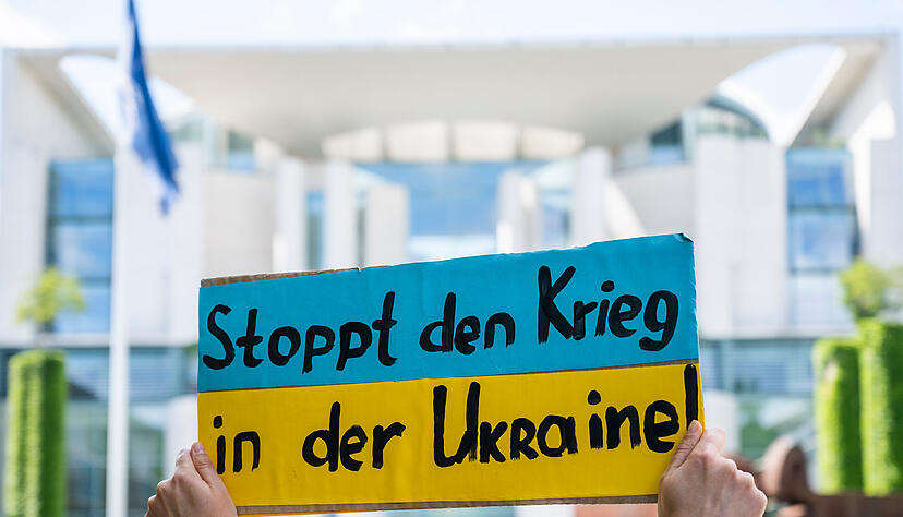 Bei einer Kundgebung für den Beitritt der Ukraine in die Europäische Union EU hält eine Demonstrantin ein Plakat mit der Aufschrift "Stoppt den Krieg in der Ukraine!" vor dem Kanzleramt.