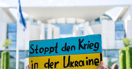 Bei einer Kundgebung für den Beitritt der Ukraine in die Europäische Union EU hält eine Demonstrantin ein Plakat mit der Aufschrift "Stoppt den Krieg in der Ukraine!" vor dem Kanzleramt.