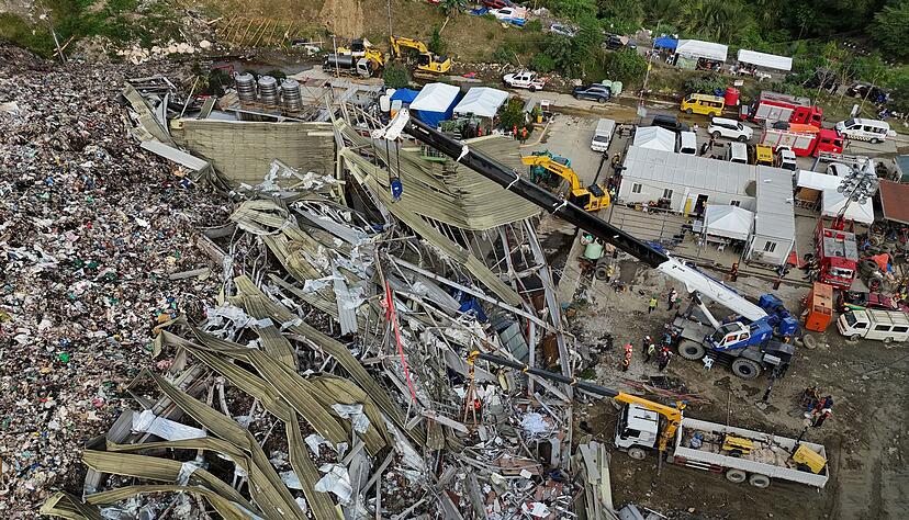 Die Einsatzkr&auml;fte suchen unter anderem mit einem Kran in den Abfall-Massen.