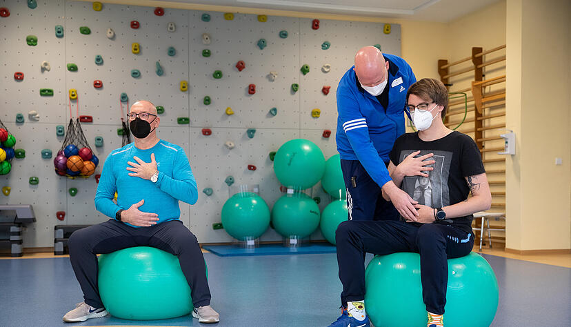 Long-Covid-Patienten beim Atemtraining mit einem Physiotherapeuten in einer Reha-Klinik für Post-Covid Erkrankte.