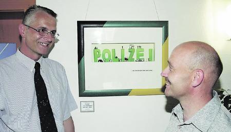 Ein Polizeibeamter stellt die Polizei witzig dar: "Stra&szlig;enpolizist" Uwe Schneider (rechts) im Gespr&auml;ch mit Polizeisprecher Torsten Weidemann vor seiner Kollage "Polizei". (Foto: Uwe Mundt)