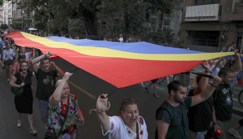 Menschen halten eine rumänische Flagge während einer Demonstration zum Gedenken an ein getötetes 15-jähriges Mädchen in Bukarest.