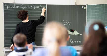 Eine Lehrerin schreibt in einer Grundschule W&ouml;rter, die mit &laquo;Sp&raquo; beginnen, an eine Tafel.