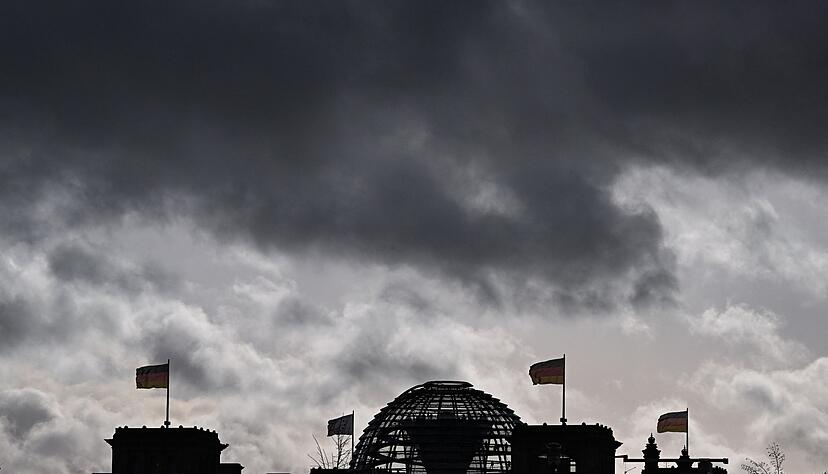 Dunkle Wolken über dem Reichstagsgebäude in Berlin: Statt verlässliche Rahmenbedingungen zu schaffen, lässt die Regierung die Unternehmen im Unklaren, meint unser Autor.