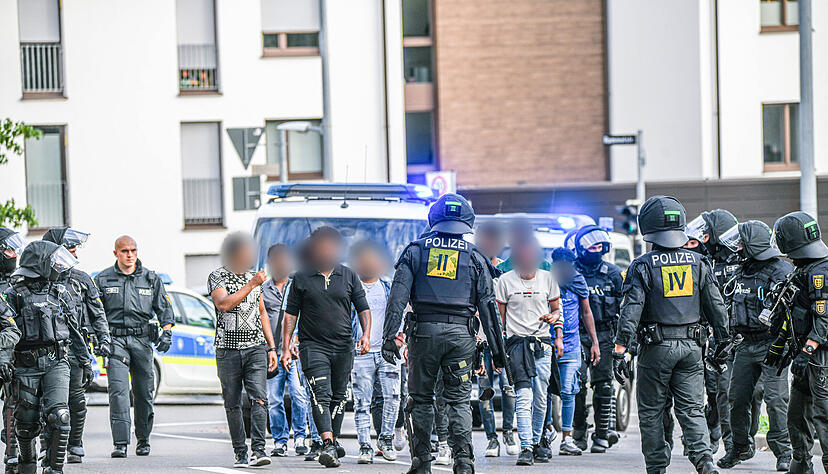 Eine Gruppe von Menschen wird nach Ausschreitungen bei einer Eritrea-Veranstaltung von Polizeikräften eskortiert.