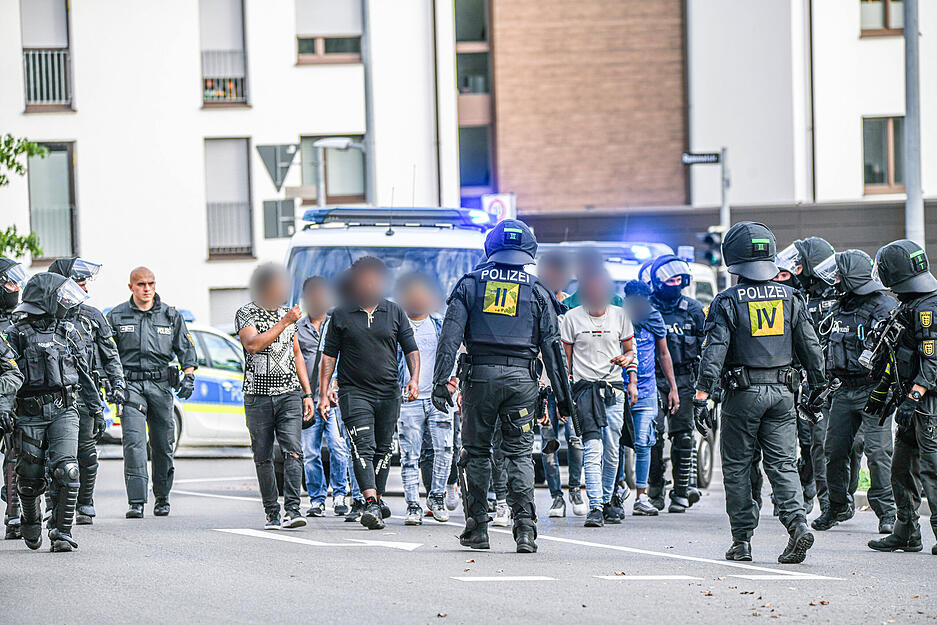 Eine Gruppe von Menschen wird nach Ausschreitungen bei einer Eritrea-Veranstaltung von Polizeikräften eskortiert.