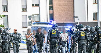 Eine Gruppe von Menschen wird nach Ausschreitungen bei einer Eritrea-Veranstaltung von Polizeikräften eskortiert.