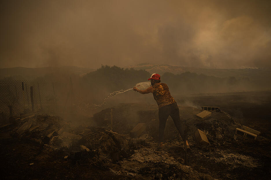 Eine Bewohnerin von Cualedro, in der Provinz Ourense, Galicien, versucht, die Reste eines Feuers um ihr Lagerhaus zu l&ouml;schen.