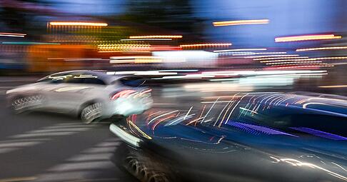 Autos fahren am Abend auf einer Kreuzung. (Wischeffekt durch Langzeitbelichtung.) (Symbolbild)