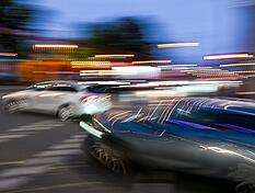 Autos fahren am Abend auf einer Kreuzung. (Wischeffekt durch Langzeitbelichtung.) (Symbolbild)