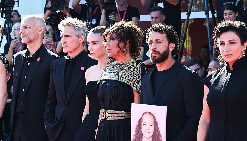 Joaquin Phoenix und Rooney Mara mit einem Teil des Filmteams und einem Foto von Hind Rajab auf dem roten Teppich. Joaquin Phoenix und Rooney Mara mit einem Teil des Filmteams und einem Foto von Hind Rajab auf dem roten Teppich.