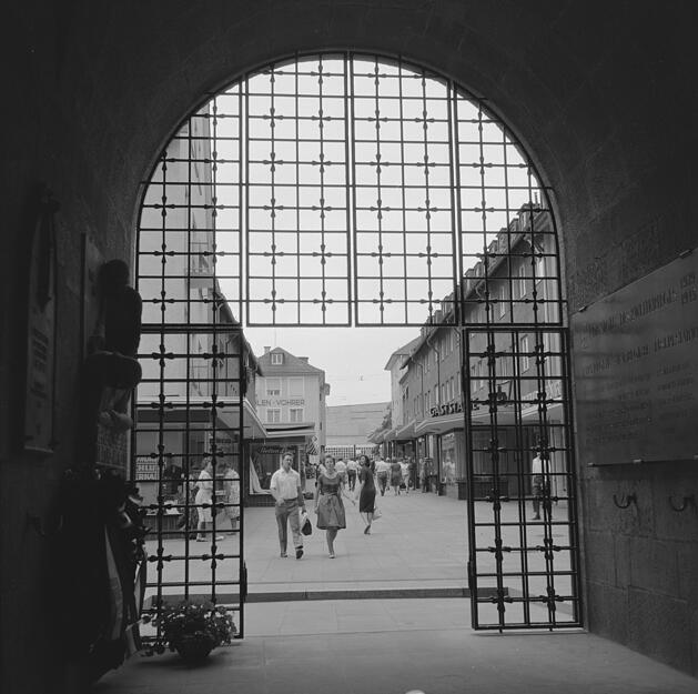 Ein Blick durch das Eisentor des Hafenmarktturmes zeigt, wie beliebt die Einkaufspassage 1964 ist.