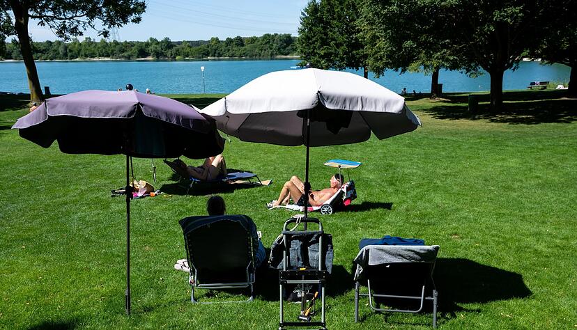 Ausflügler genießen das hochsommerliche Wetter unter Sonnenschirmen am Echinger See. Ausflügler genießen das hochsommerliche Wetter unter Sonnenschirmen am Echinger See.