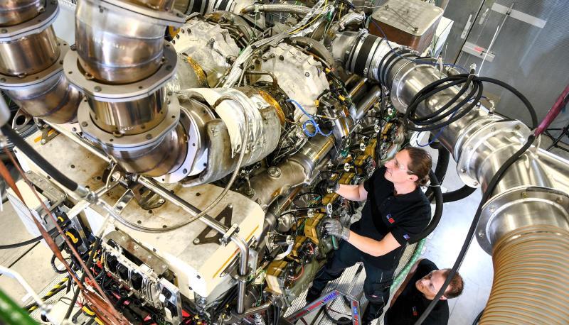 Ein Techniker und zwei Ingenieure arbeiten in einem MTU-Prüfstand an einem Rolls-Royce-Motor. Ein Techniker und zwei Ingenieure arbeiten in einem MTU-Prüfstand an einem Rolls-Royce-Motor.