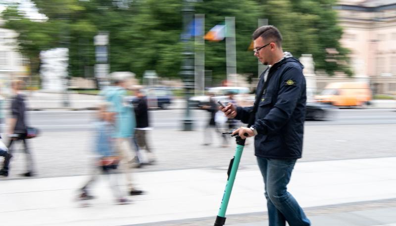 Auf zwei winzigen Rädern im Innenstadtverkehr, die Augen fest aufs Handy geheftet: Ein Tourist fährt durch Berlin-Mitte.