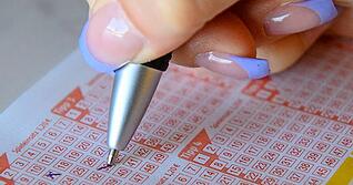 Eine Frau füllt einen Lottoschein aus. (Symbolbild)