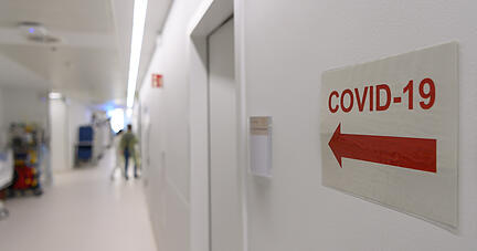 Ein Richtungspfeil zum "Covid-19" Bereich klebt vor einer Corona-Intensivstation an der Wand. Foto: dpa