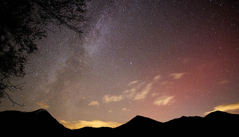 Polarlichter schimmern am Sternenhimmel über den Bergen am Walchensee in Bayern.