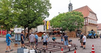Die Mitglieder der Freiwilligen Feuerwehr Erlenbach-Binswangen bei der Arbeit: Beim Aufbau der H&uuml;tte macht vor allem das unebene Kopfsteinpflaster Probleme. Doch gemeinsam und mit genug Material zum Unterlegen klappt es schlie&szlig;lich.