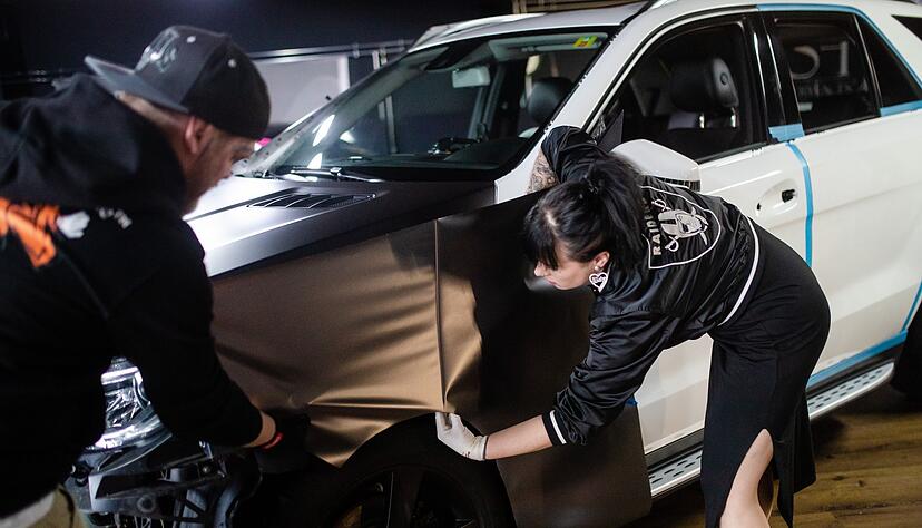 Teamwork: Michael und Coco Mulansky (r) arbeiten an einem Auto und bringen die Folie auf. Teamwork: Michael und Coco Mulansky (r) arbeiten an einem Auto und bringen die Folie auf.