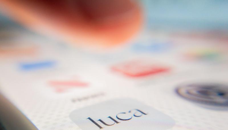 Eine Person zeigt auf einem Smartphone auf das Symbol der Luca-App.
