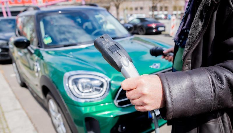 Ein Mann entfernt an einem Auto mit Plug-in-Hybrid-Antrieb in Berlin-Mitte das Ladekabel (Symbol). Ein Mann entfernt an einem Auto mit Plug-in-Hybrid-Antrieb in Berlin-Mitte das Ladekabel (Symbol).