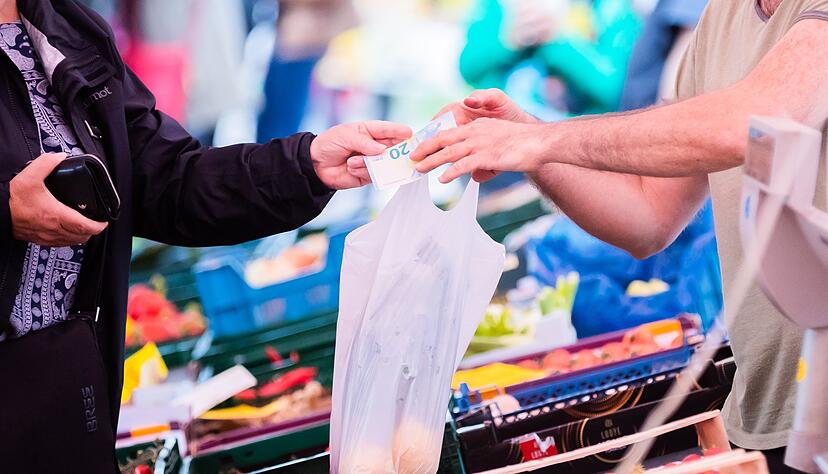 Eine Kundin bezahlt auf einem Wochenmarkt im Berliner Ortsteil Sch&ouml;neberg an einem Obst- und Gem&uuml;sestand.