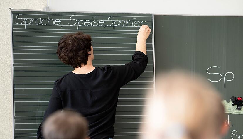 Eine Lehrerin schreibt in einer Schule Worte an eine Tafel. Eine Lehrerin schreibt in einer Schule Worte an eine Tafel.