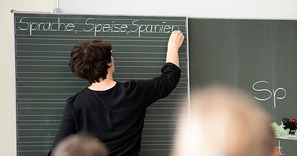Eine Lehrerin schreibt in einer Schule Worte an eine Tafel.