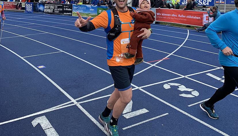 Gewann einen Preis: Andreas K&uuml;hner &uuml;berquert mit seiner Tochter Jule im Arm die Ziellinie.