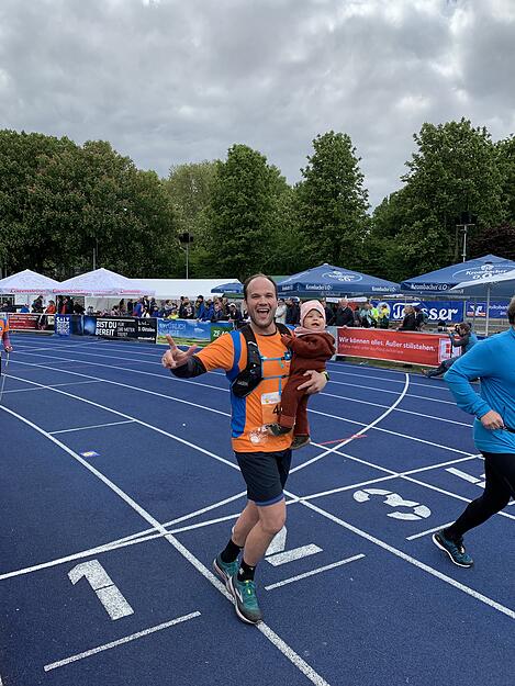 Gewann einen Preis: Andreas K&uuml;hner &uuml;berquert mit seiner Tochter Jule im Arm die Ziellinie.