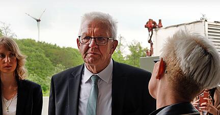 Ministerpräsident Winfried Kretschmann im Gespräch mit der Vorstandsvorsitzenden des DLR, Anke Kaysser-Pyzalla. Im Hintergrund ein Windrad im Harthäuser Wald.