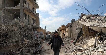 Ein Mann geht an eingestürzten Gebäuden im syrischen Jinderis vorbei. Ein Mann geht an eingestürzten Gebäuden im syrischen Jinderis vorbei.